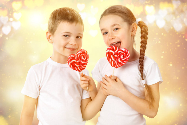 Kleine jongen en meisje met snoep rode lolly in hart vorm. Valentijnsdag kunst portret. - Foto, afbeelding