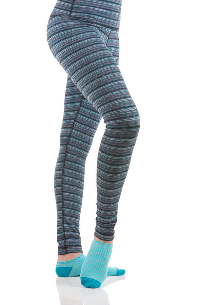 Vue rapprochée des jambes de femme en pantalon thermique rayé coloré et chaussettes bleues de la vue latérale debout sur une jambe avec l'autre jambe relevée
 - Photo, image