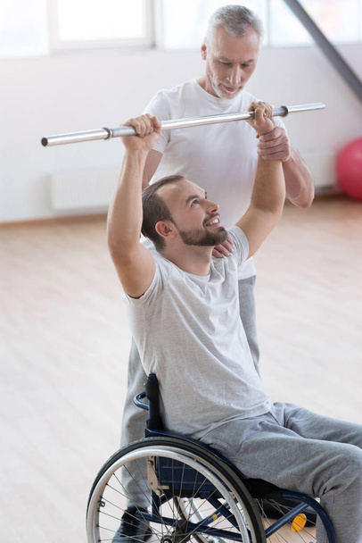 Masterful aged general practitioner training the disabled in the gym - Фото, изображение