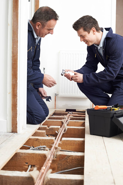 Plumber And Apprentice Fitting Central Heating in House - Фото, зображення