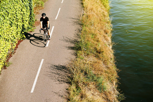Erwachsener Mann fährt Fahrrad über Antenne in der Nähe des Flusses Frankreich - Foto, Bild