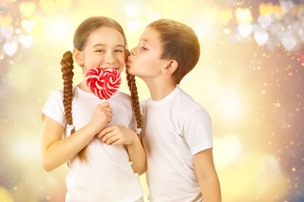 Αγόρι φιλιά κοριτσάκι με καραμέλα κόκκινη γλειφιτζούρι σε σχήμα καρδιάς. Ημέρα του Αγίου Βαλεντίνου τέχνης πορτρέτο - Φωτογραφία, εικόνα
