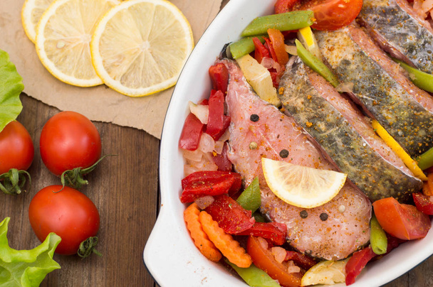 Zeebaars met groenten. Gemarineerde vis met groenten voor het koken in de oven. Houten achtergrond. Bovenaanzicht. Close-up - Foto, afbeelding