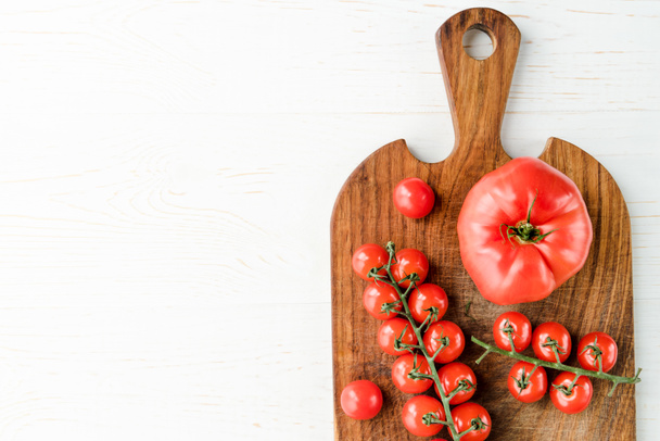 Tomatoes and cutting board   - Фото, изображение