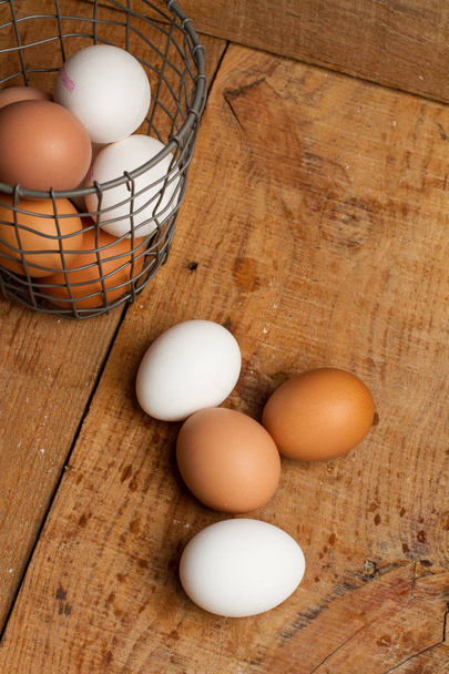 Τα αυγά σε ένα καλάθι και σε ένα ξύλινο τραπέζι - Φωτογραφία, εικόνα
