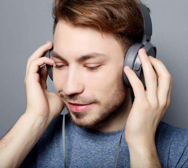 Happy young stylish man  adjusting his headphones ad smiling wh - Fotoğraf, Görsel