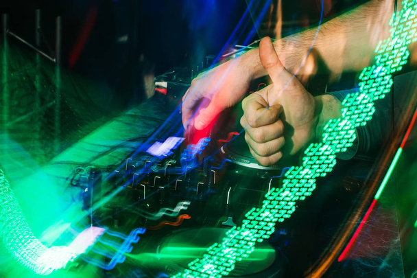 DJ gra muzykę na mikser w nocnym klubie z niewyraźne tło - Zdjęcie, obraz