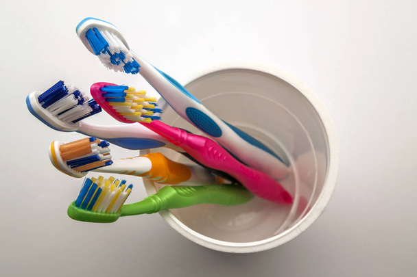 Close up shot of set of multicolored toothbrushes in glass on cl - Photo, Image