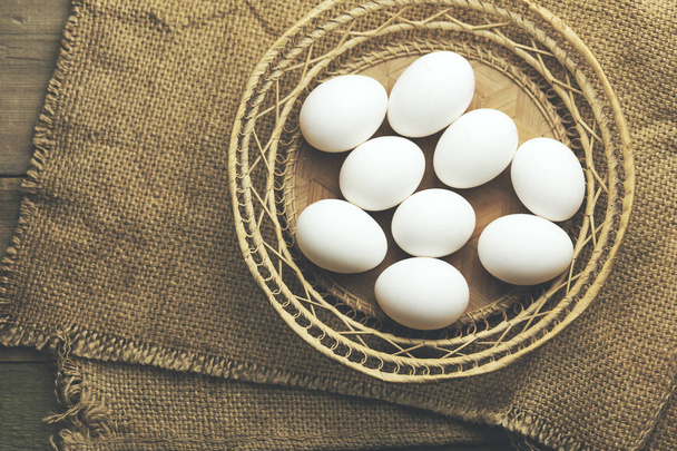 Eggs in basket on wooden background - Valokuva, kuva