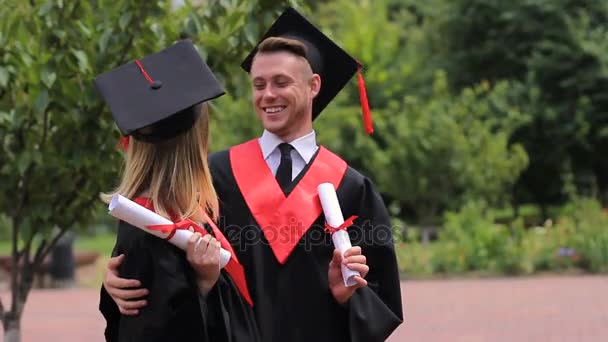 Alegre pareja de graduados con diplomas y posando para la cámara, estudiantes
 - Metraje, vídeo