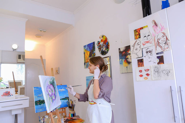 schöne junge Malerin malt Bild verwendet Pinsel und Öl, und - Foto, Bild