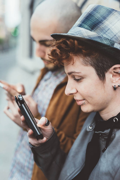 άντρας και γυναίκα στην πόλη χρησιμοποιώντας smartphones - Φωτογραφία, εικόνα