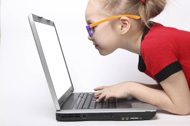 girl stares at the laptop and typing on the keyboard. isolated white background. orange glasses - Photo, Image