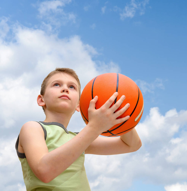 Küçük çocuk basketbol ile mavi gökyüzü arka plan üzerinde - Fotoğraf, Görsel