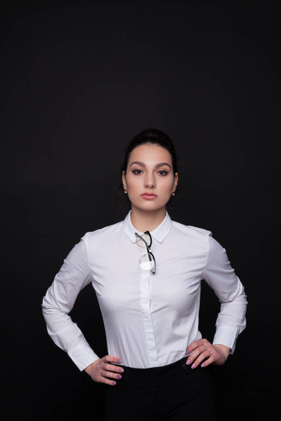Молодая успешная деловая женщина. Девушка на черном фоне в белой блузке
 - Фото, изображение