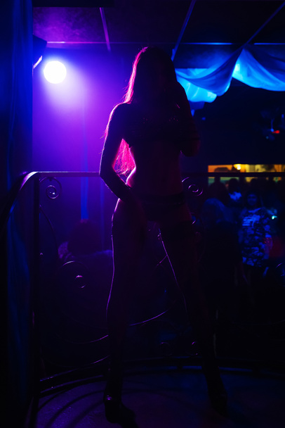 Tänzer Silhouette schlank posiert auf der Bühne im Club bei Party im Rampenlicht - Foto, Bild