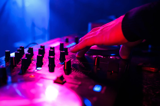 DJ играет на миксере на вечеринке на размытом красочном фоне крупным планом
 - Фото, изображение