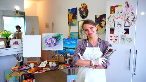 Cute Female Painter Looking at Camera, Smiling in Hand Big and Small Brush For Oil Paints, Stands in Spacious Art Studio. - Footage, Video