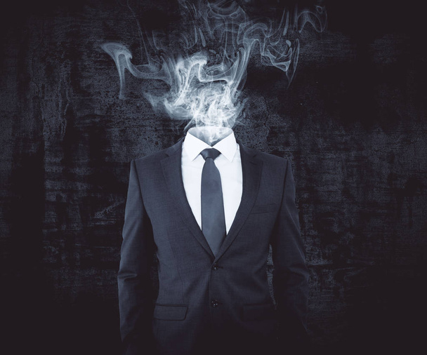 Businessman with smoke intead of head on dark background. Confusion concept - Valokuva, kuva