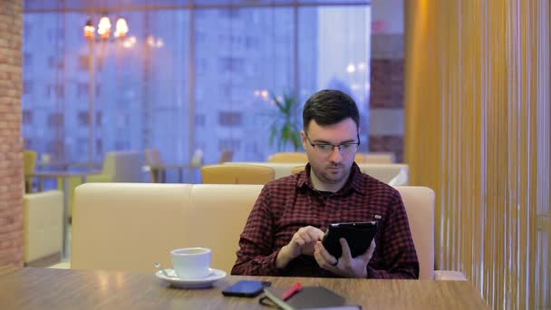 Adult man with smartphone and tablet during breakfast in cafe - Materiał filmowy, wideo