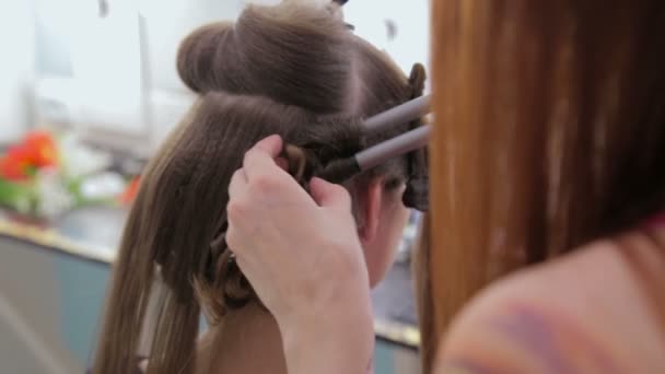 Professional hairdresser doing hairstyle for pretty teen girl - Footage, Video