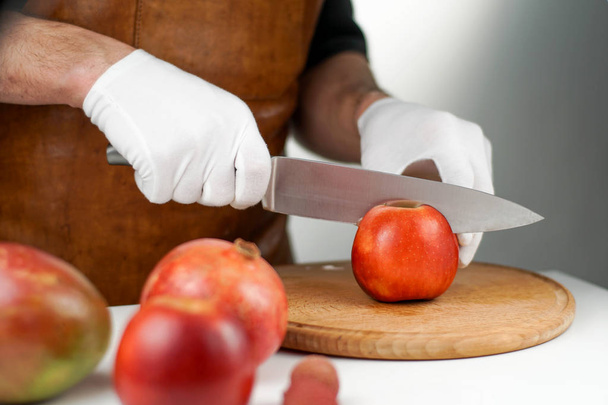 Big knife cutting juicy apple on a white table. Dieting and healthy lifestyle concept - Fotó, kép