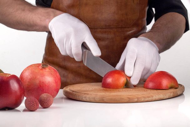 Cutting an apple into pieces on a wooden cutting board. Composition of fruits - Foto, imagen