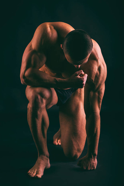 cuerpo masculino muscular sobre un fondo oscuro
. - Foto, Imagen