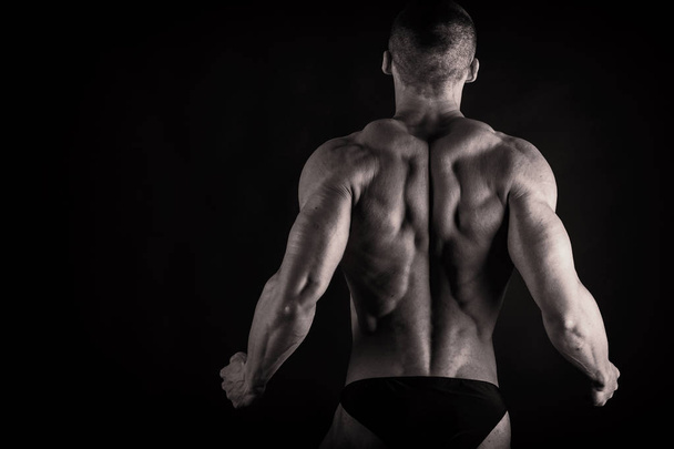 A man with a gorgeous muscular body on a black background - Foto, imagen
