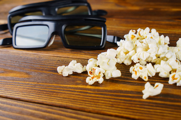 lockeres Popcorn und 3D-Gläser auf einem hölzernen Hintergrund - Foto, Bild
