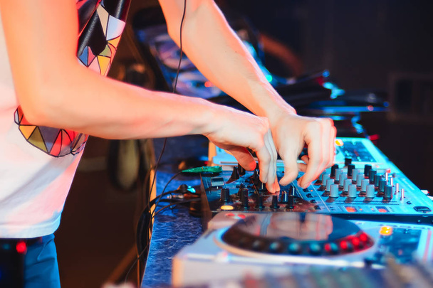 hands of DJ on mixer playing club music at party - Photo, Image