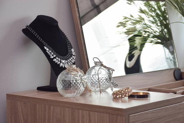 Bangles necklace and crystal jars on wooden dressing table - Foto, afbeelding