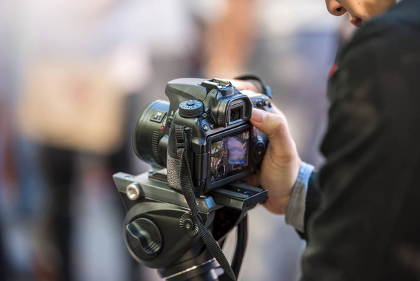 jonge mannen neemt video met camera op statief  - Foto, afbeelding