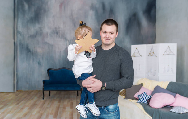 Happy father holding hes daughter. Girl holds star in hand. - Zdjęcie, obraz