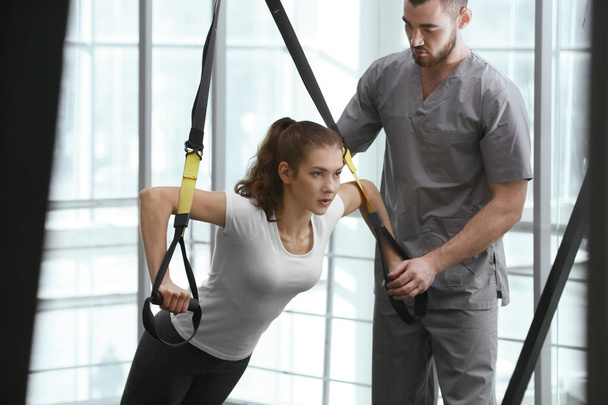 Rehabilitation concept. Young woman doing exercises under physiotherapist supervision - Fotografie, Obrázek