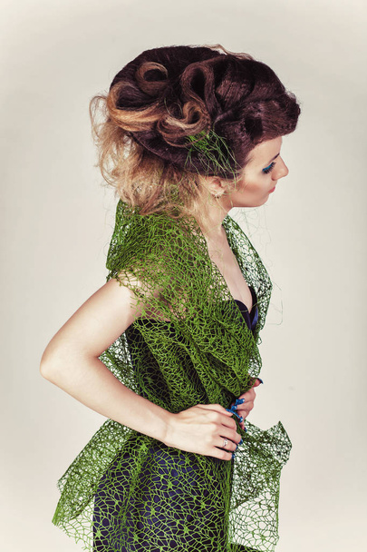 schönes Modell mit großer Frisur in grünem Mesh und blauem Kleid. Frau mit langen blauen Nägeln - Foto, Bild