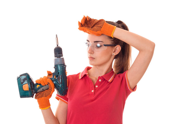 portrait of tired brunette lady builder makes renovation with drill in hands isolated on white background - Foto, imagen