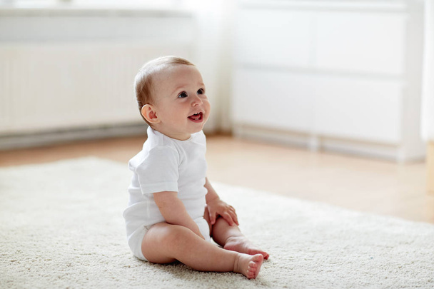 happy baby boy or girl sitting on floor at home - Fotó, kép