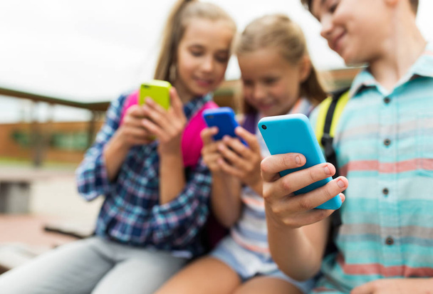 elementary school students with smartphones - Фото, зображення