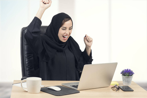 Young Arabian businesswoman expressing success at office - 写真・画像