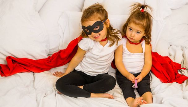 Две маленькие девочки играют в супергероев
 - Фото, изображение