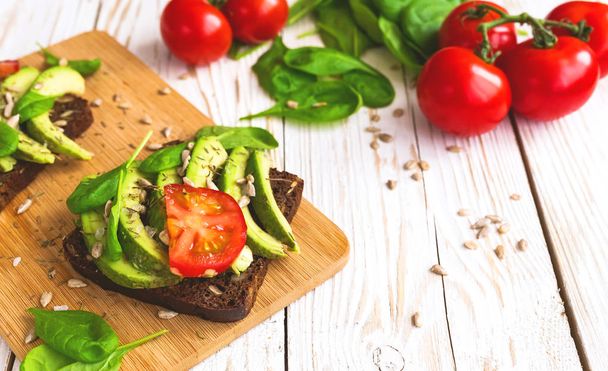 Toast with sliced avocado, tomatoes, spinach and spices - 写真・画像