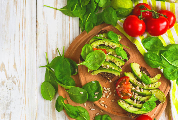 Toast with sliced avocado, tomatoes, spinach and spices - Foto, Bild