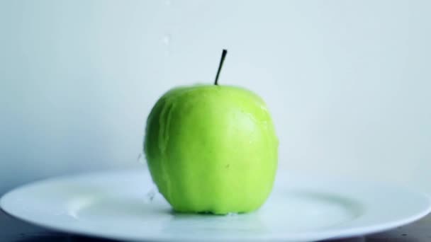 Apple op de plaat. Druppels water vallen op een groene appel. - Video