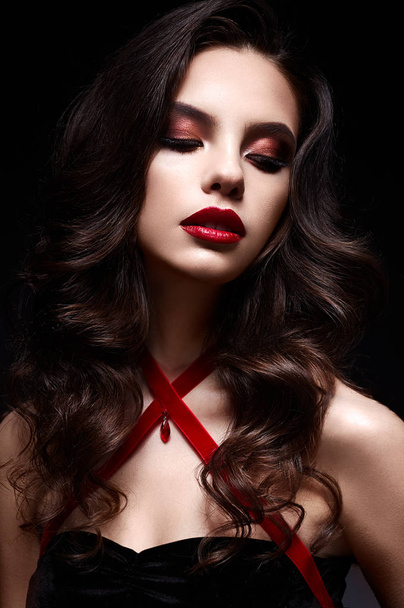 Young girl with a black lace mask on her face and a pendant in the form of heart on the neck. Beautiful model with bright make-up, red lips and curls. - Fotografie, Obrázek