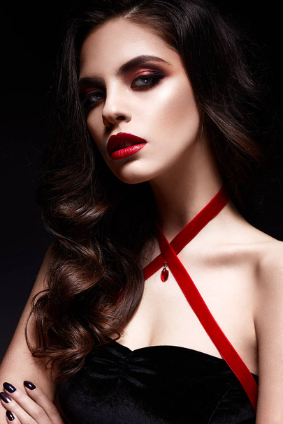 Young girl with a black lace mask on her face and a pendant in the form of heart on the neck. Beautiful model with bright make-up, red lips and curls. - Foto, Imagem