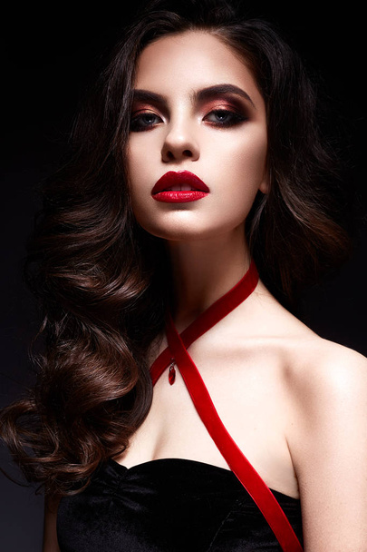 Young girl with a black lace mask on her face and a pendant in the form of heart on the neck. Beautiful model with bright make-up, red lips and curls. - 写真・画像