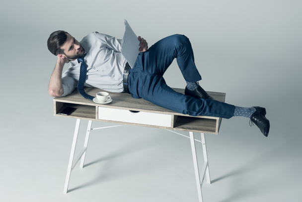 businessman lying on table - 写真・画像