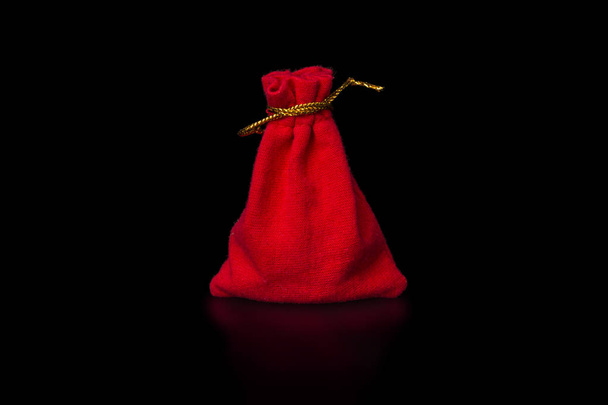 Rode fluwelen zakje om sieraden en delicate objecten geïsoleerd op zwarte achtergrond.  - Foto, afbeelding