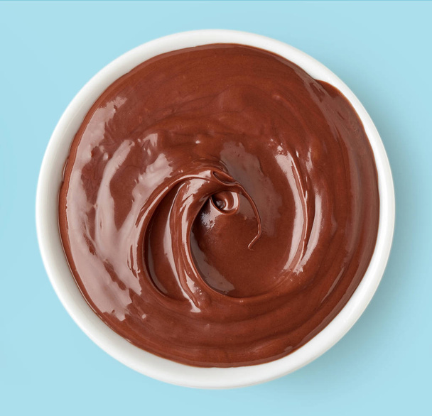 Schokoladencreme in einer runden Schale auf blauem Hintergrund - Foto, Bild